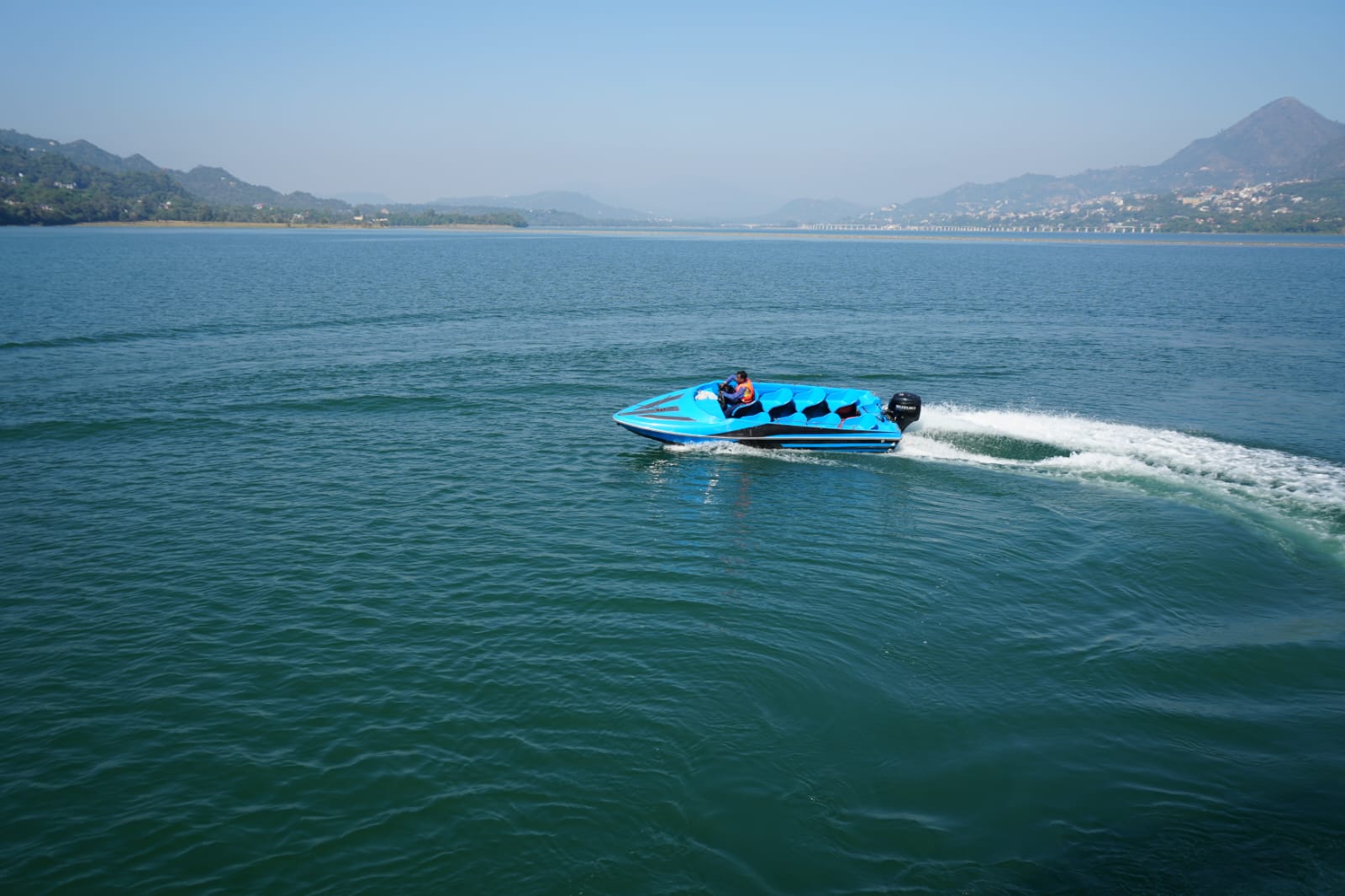 Blue speed boat crossing the Satluj River with mountain views